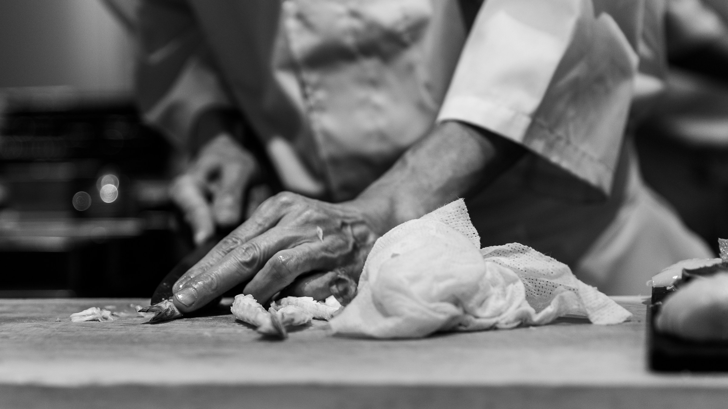 Chef hands preparing fish with a Japanese knife